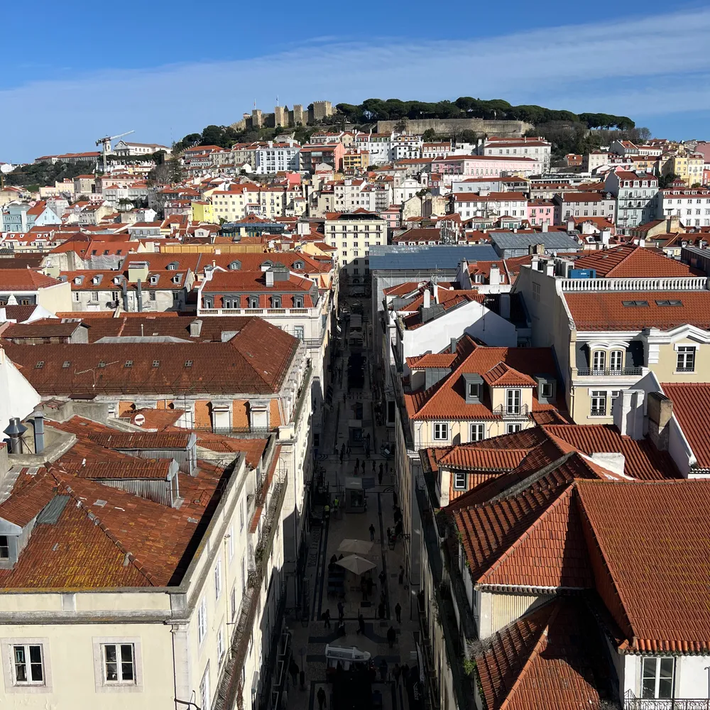 Lisbon's red-tiled rooftops from above, the castle on the hill behind
